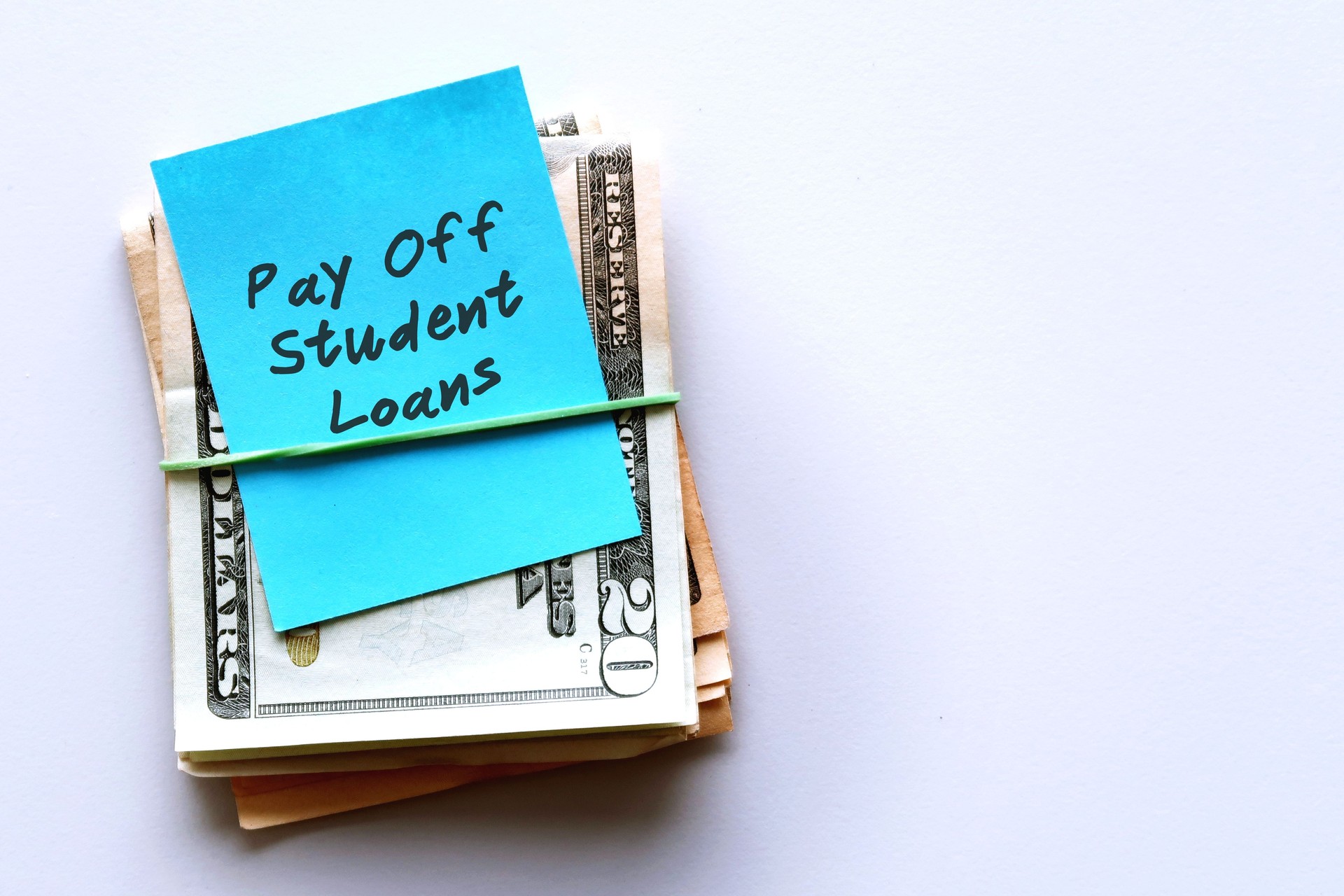 Cash dollars money with blue note written Pay Off Student Loans , concept of financial management strategy .set aside amount money to pay more than minimum , extra payment to help pay off faster